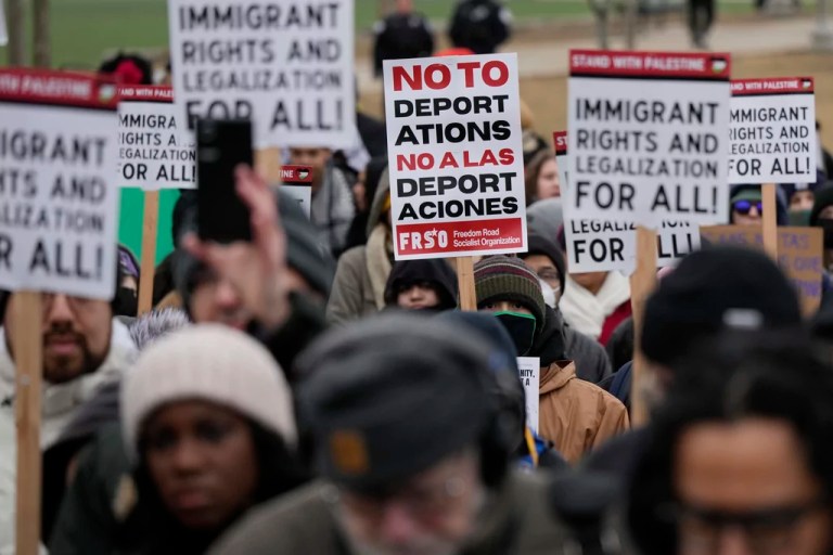 People hold signs and listen to speakers during the Stop The Attacks on Immigrants protest in Chicago, Saturday, Feb. 8, 2025.